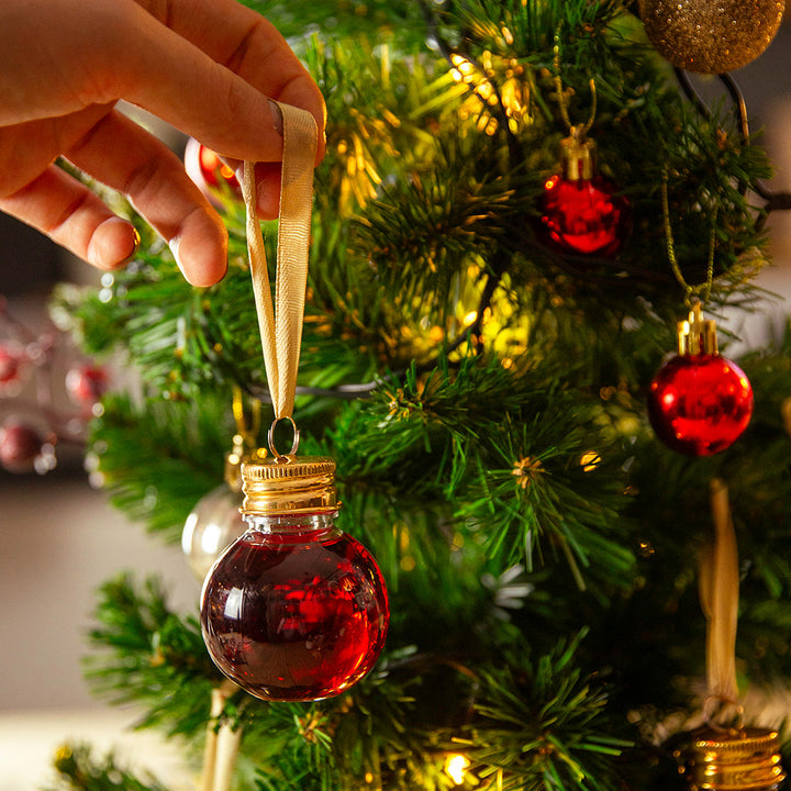 Someone hanging a gin filled Bauble on a Christmas tree
