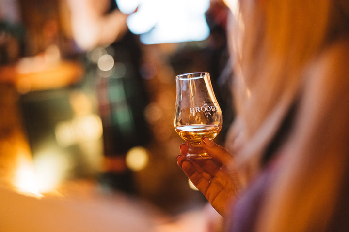 Someone holding a dram of The Broody Hen Scotch Whisky