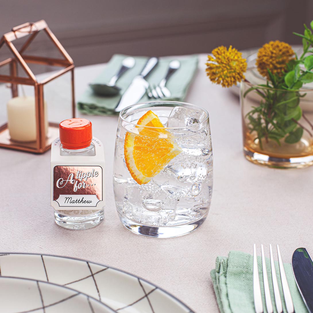 miniature bottle of Pickering's Original 1947 Gin next to a gin and tonic on a dinner table