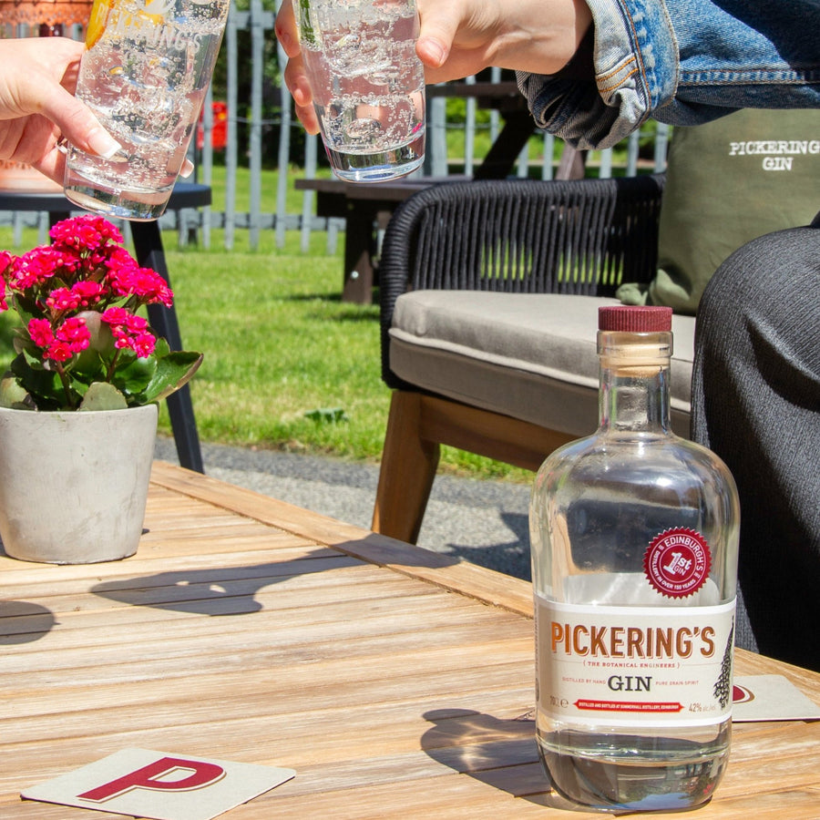 Bottle of Pickering's Gin on a table with two people cheersing in the background