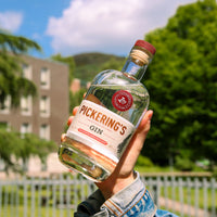 Someone holding up a bottle of Pickering's Gin with Arthurs Seat in the background