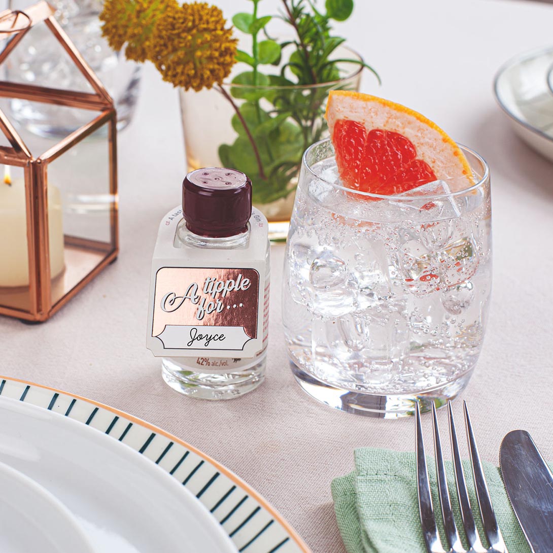 miniature bottle of Pickering's Gin next to a gin and tonic on a dinner table