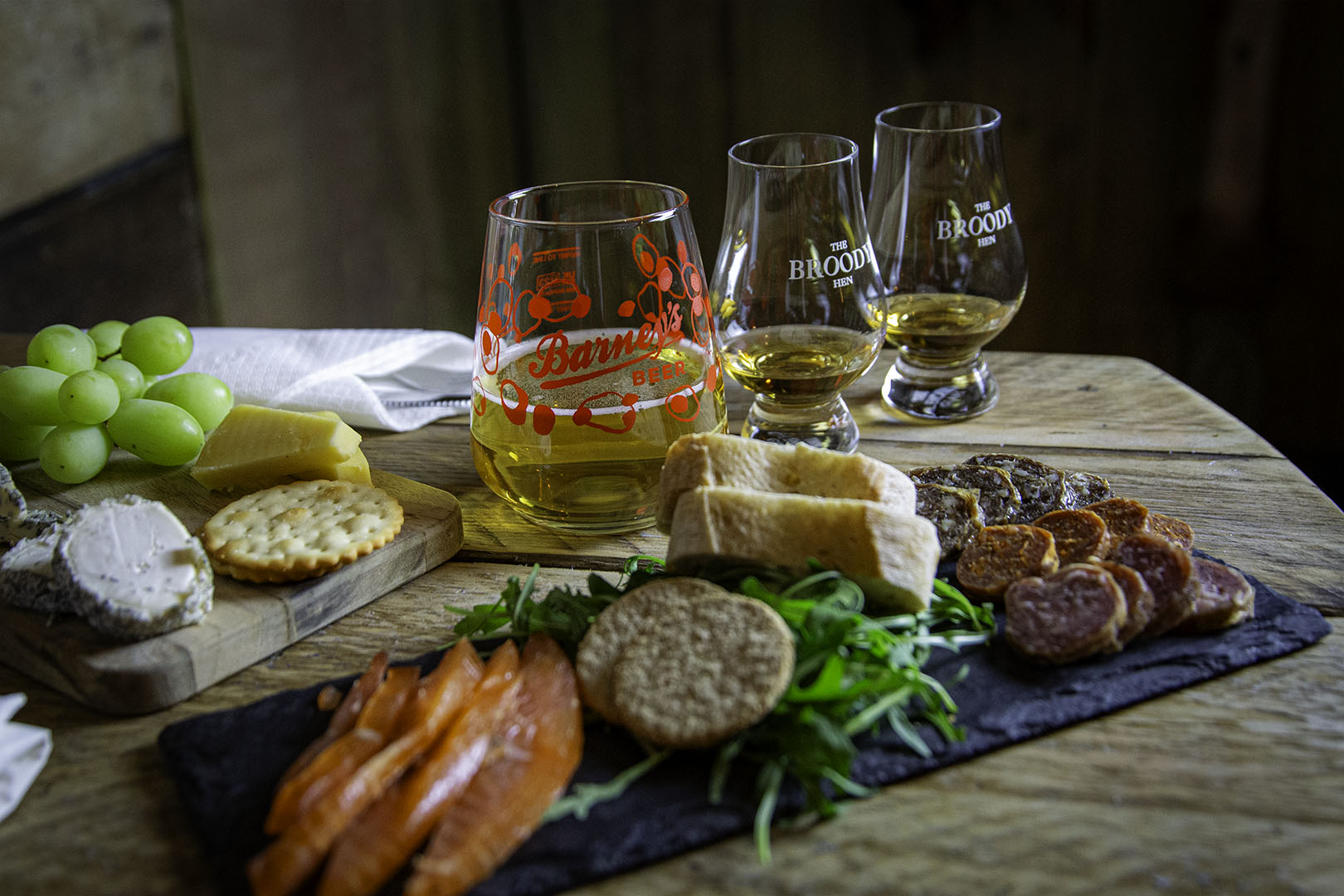 Glasses of beer and a charcuterie board with cheese, crackers, and meats.