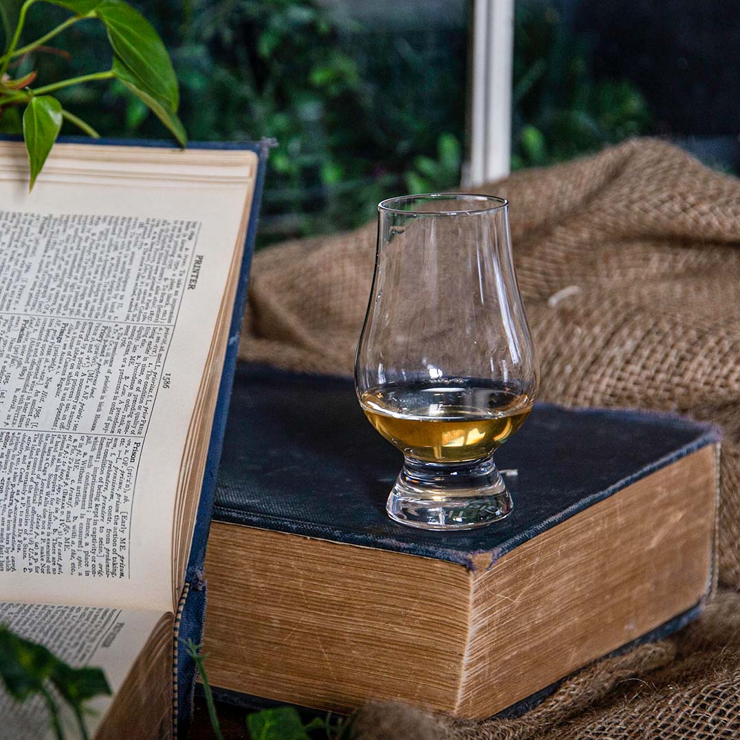 Dram of The Broody Hen Whisky on a book