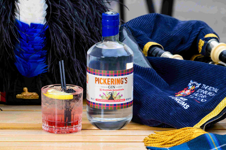 Bottle of Pickering's Gin with a cocktail and a hat on a wooden surface